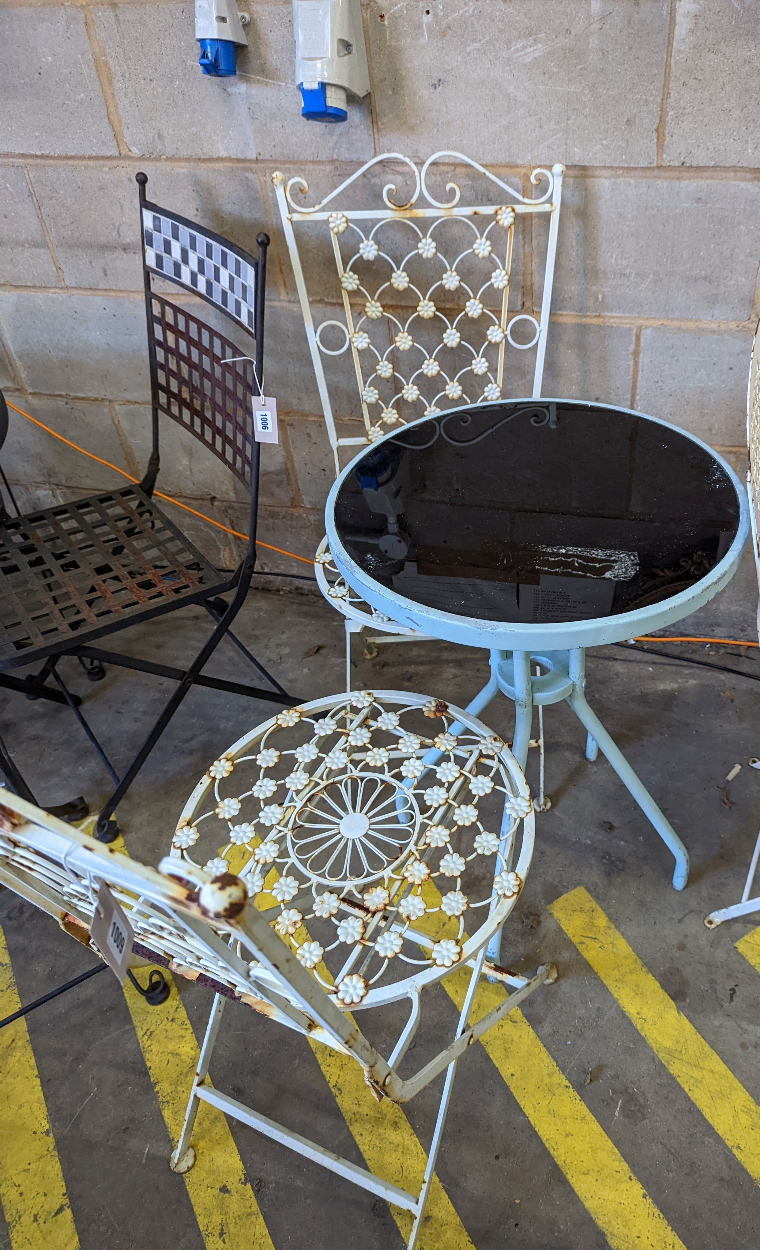 A circular glass top bistro table, diameter 50cm, height 72cm together with two painted metal chairs